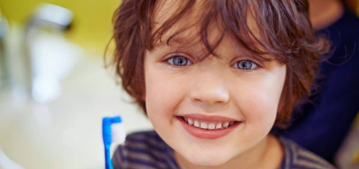 Kid smiling with tooth brush in hand