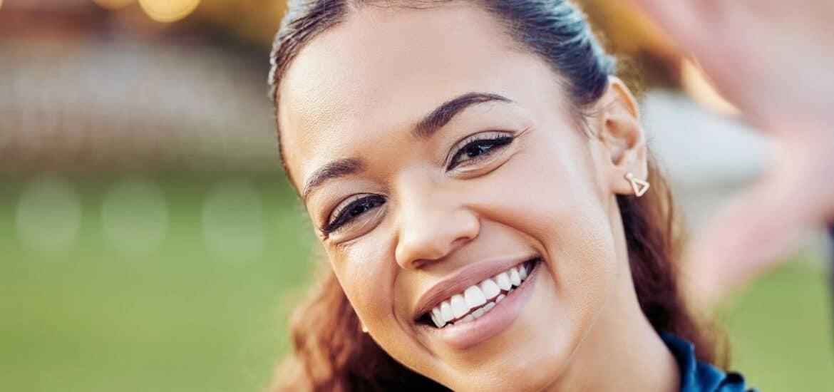 Close-up photo of a young woman with a genuine, bright smile and white teeth