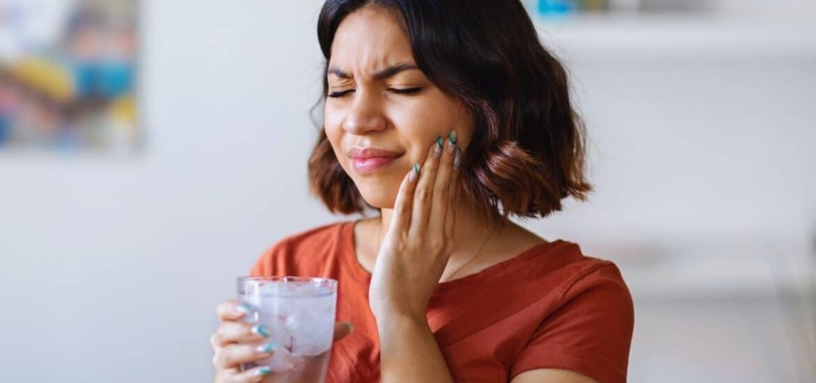 Woman wincing from tooth sensitivity pain