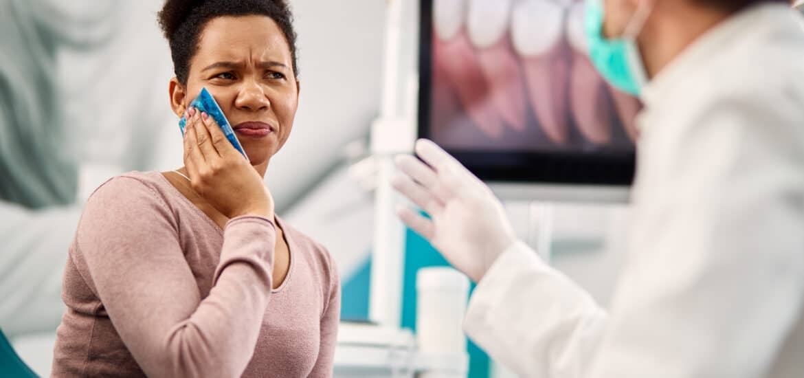 Woman with severe tooth pain speaking with an emergency dentist during an urgent dental visit.