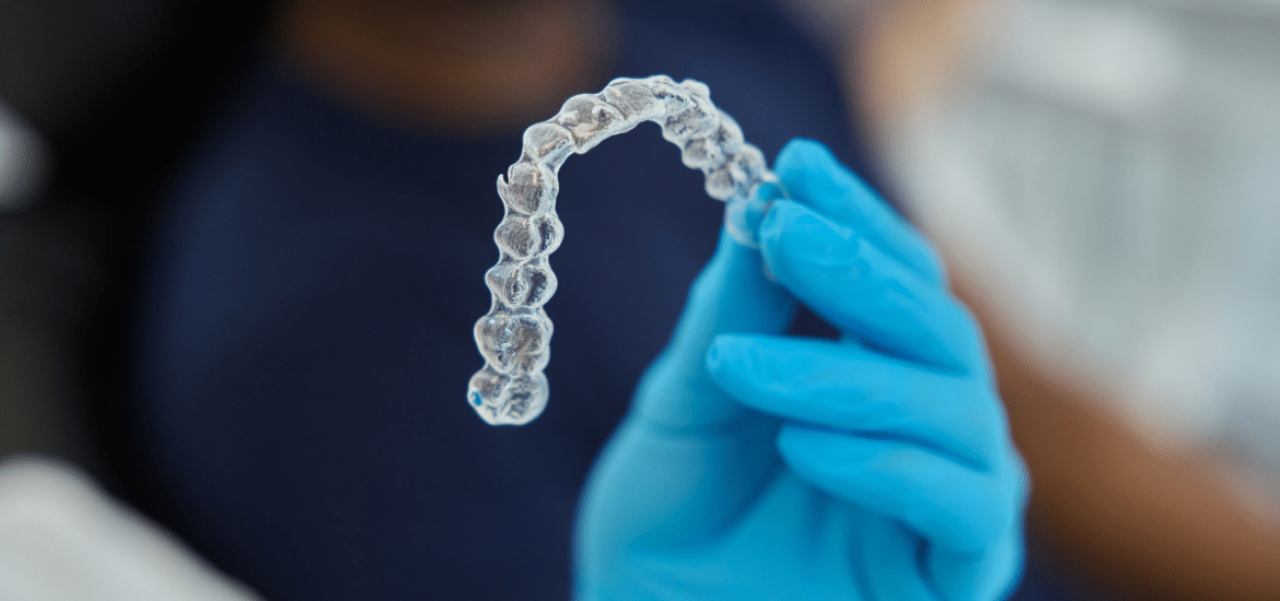 Dentist holding clear Invisalign aligner tray during orthodontic treatment consultation.