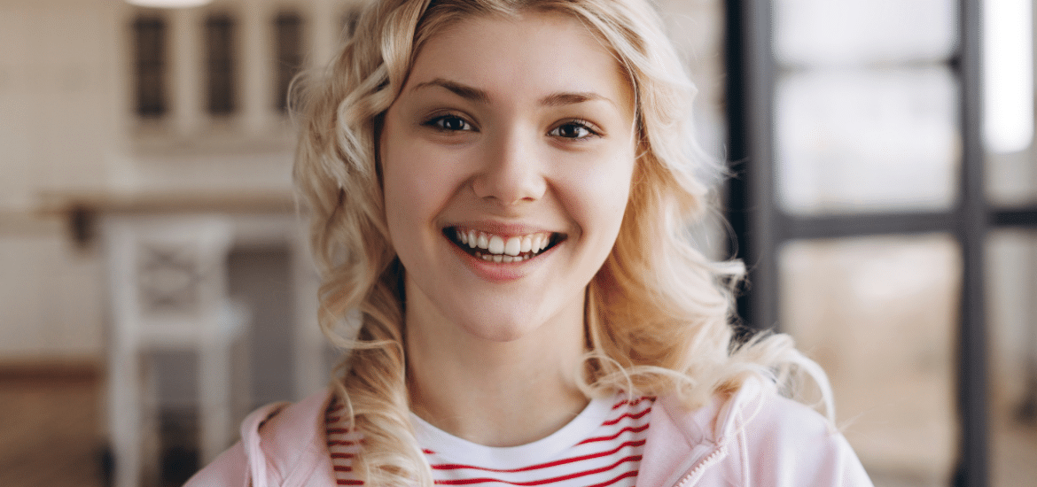 Happy young patient smiling in modern dental office setting.